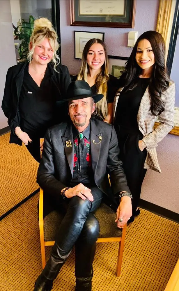 A stylish group portrait featuring three women and a man in a hat and blazer.