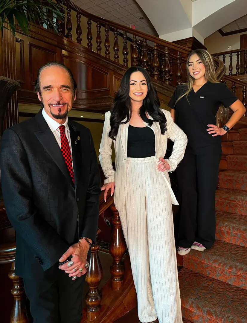 Three people posing on ornate wooden staircase