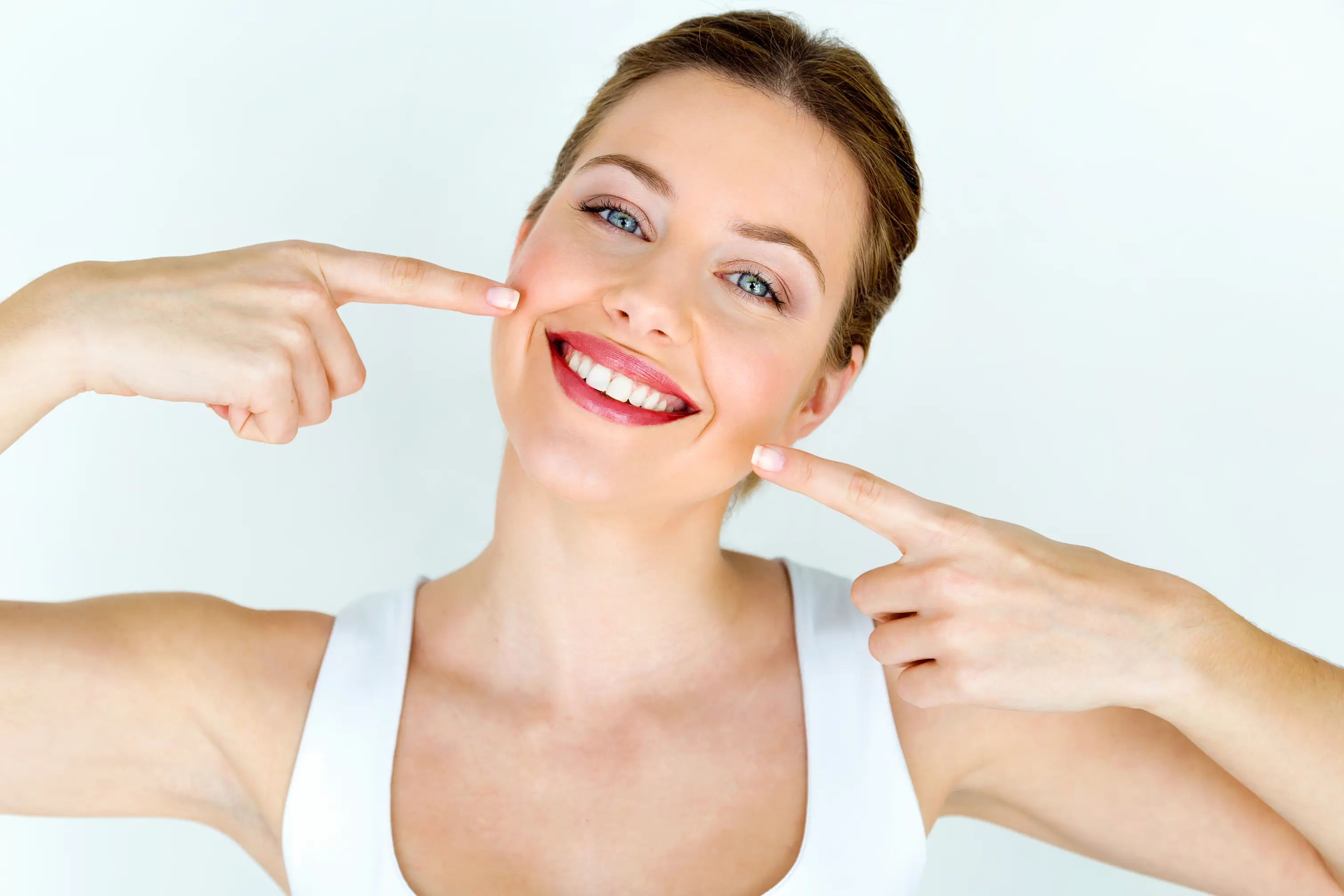 Smiling woman pointing at her teeth.